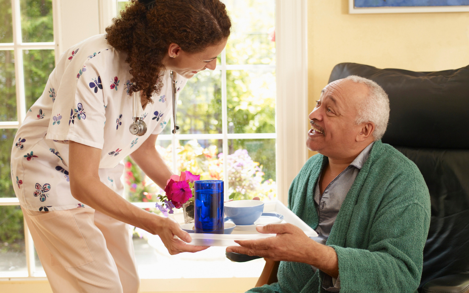 Caregiver providing a calm medication reminder as part of a morning routine for a senior at home